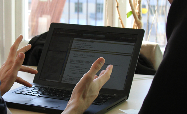 Två händer syns arbete vid en laptop.