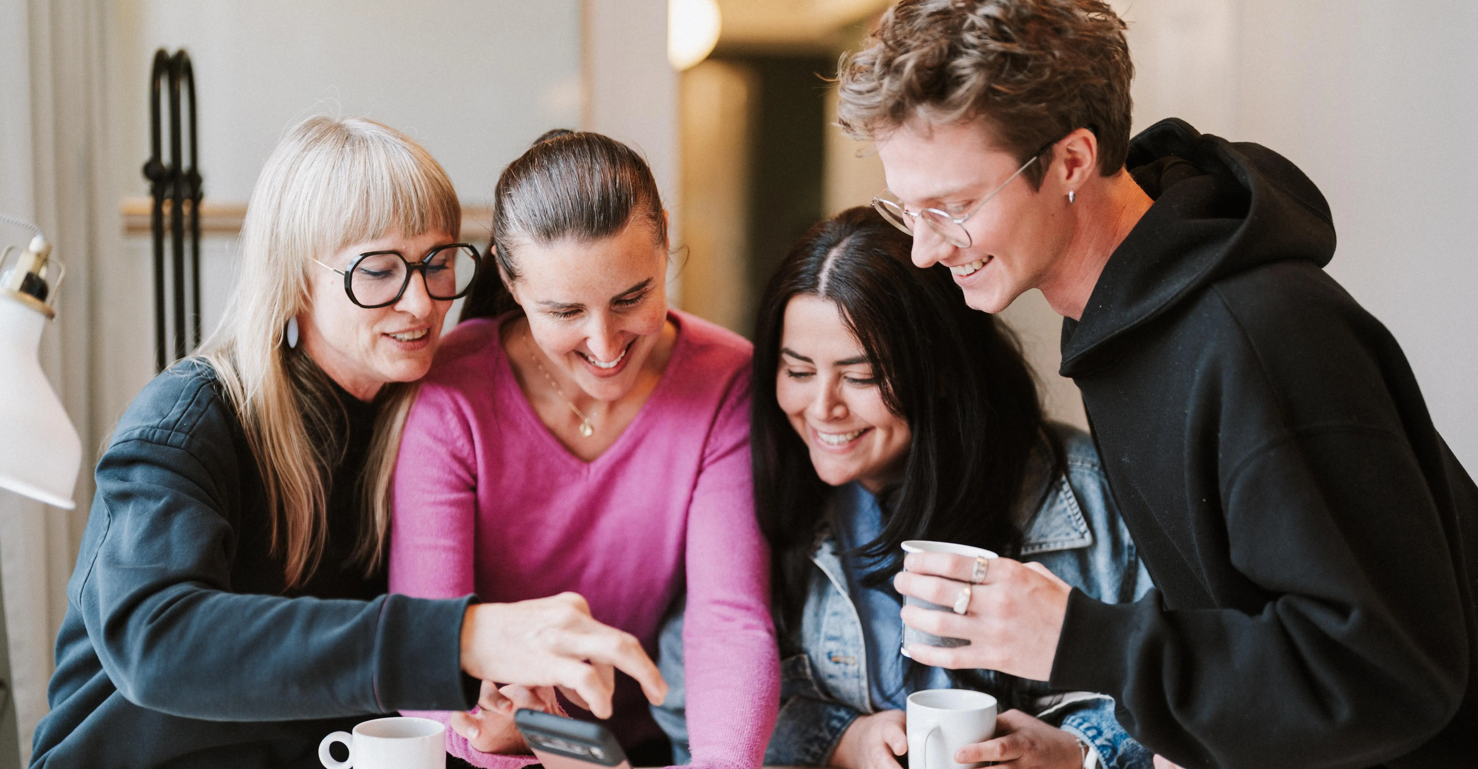 Fyra personer står vid ett bord och pratar och ler.