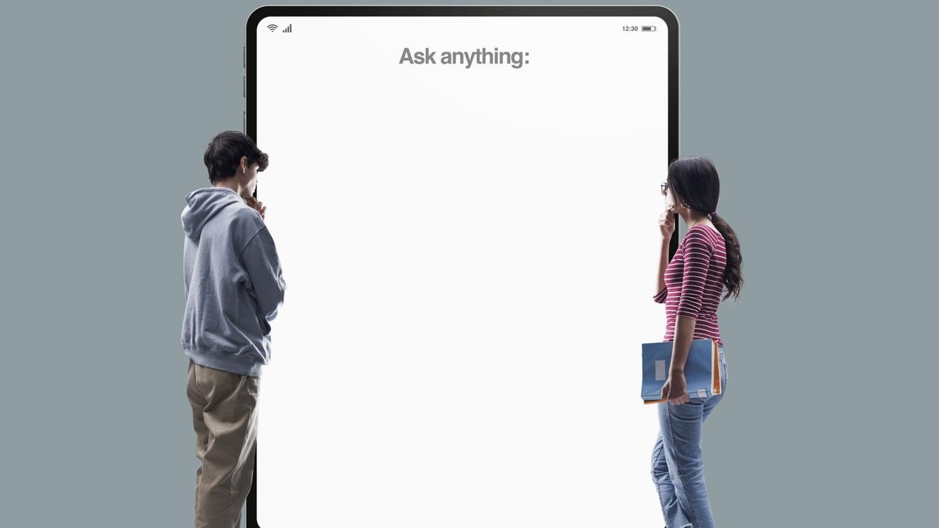 Två studenter står framför en Ipad med orden "Ask anything"